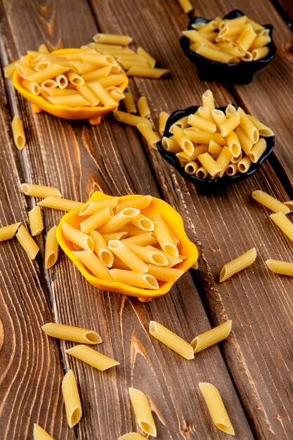 Top view penne pasta on wooden background