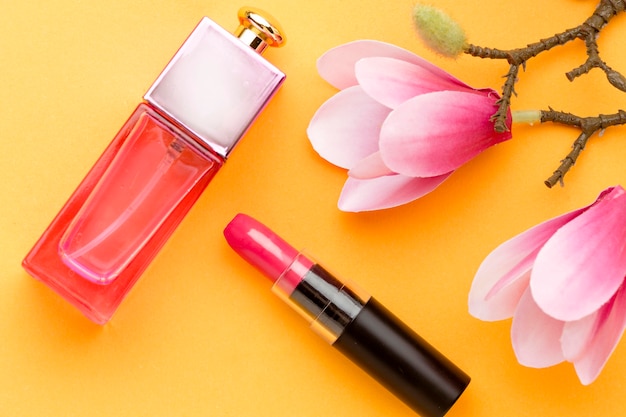 Top view perfume with lipstick and flowers