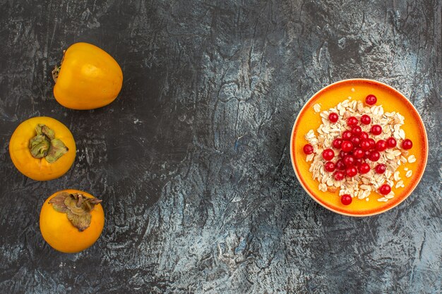 Top view persimmons the appetizing persimmons next to the bowl of berries on the table