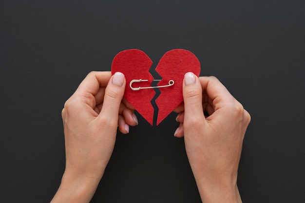 Top view of person holding broken heart put back together with safety pin