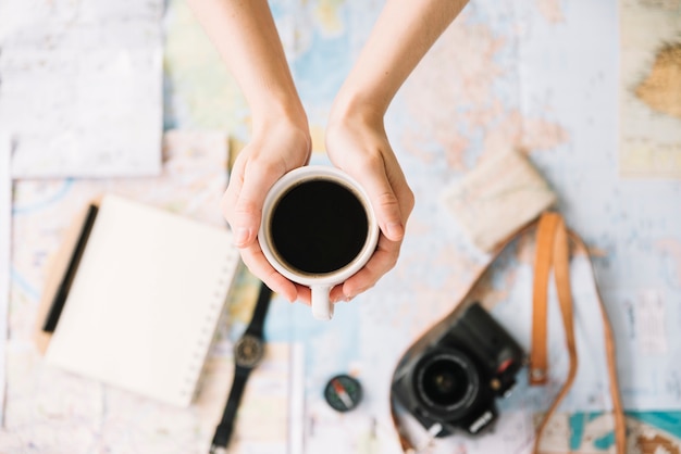 Free photo top view of a person's hand holding coffee cup over the blurred world travel map