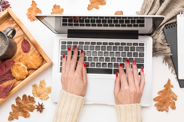 Free photo top view of person working on laptop with autumn leaves