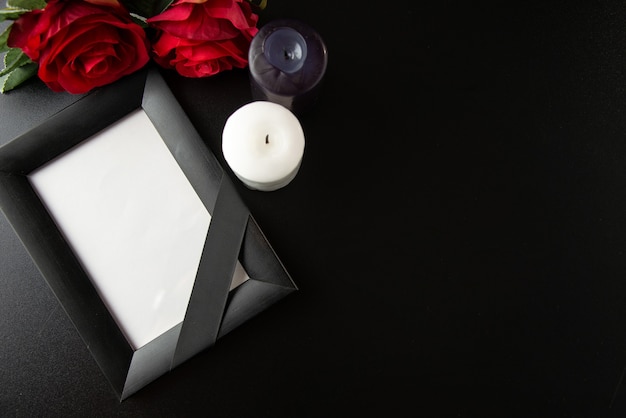 Top view of picture frame with red flowers and candles on dark wall