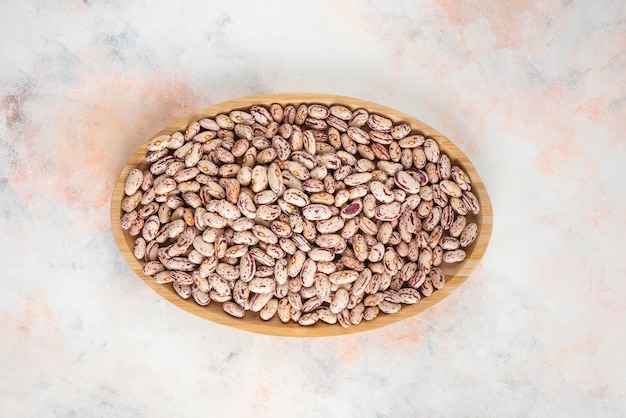 Top view of Pile of beans in wooden plate over white table.