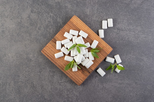 Top view of pile of gums with mint leaves over wooden board. 