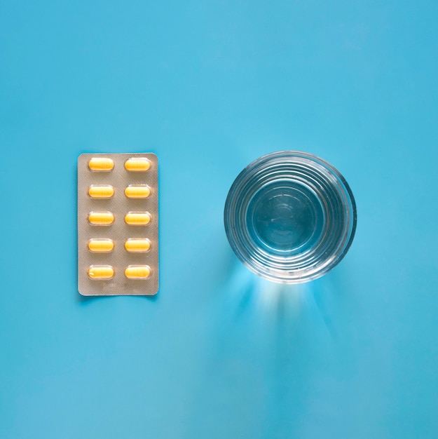 Free photo top view of pill foil with glass of water