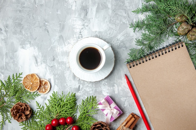 Free photo top view pine tree branches cup of tea small gifts xmas tree toys notebook pencil on grey background