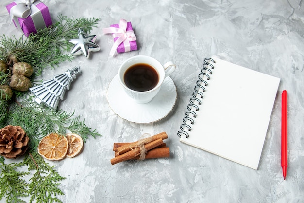 Top view pine tree branches notebook pencil cup of tea pinecones small gifts on grey background