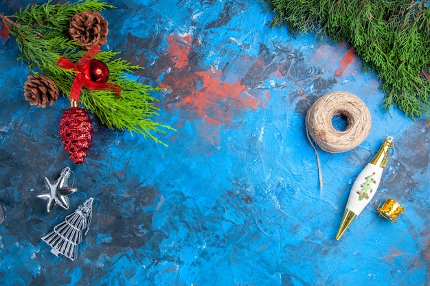 Top view pine tree branches with pinecones hanging ornaments straw thread on blue-red surface