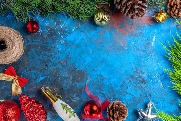 Top view pine tree branches with pinecones straw thread xmas hanging ornaments on blue-red surface