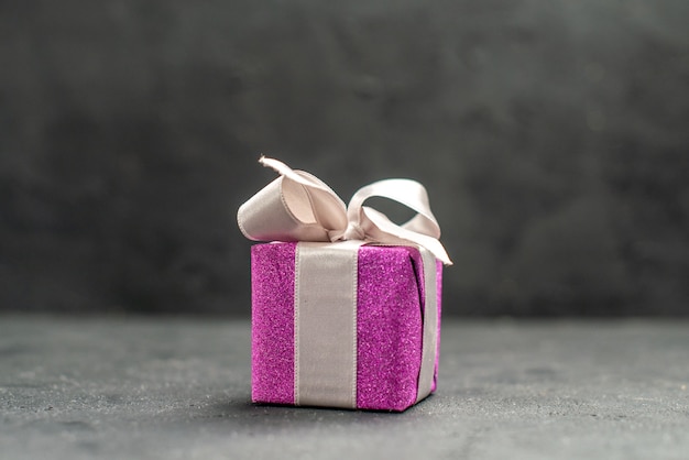 Top view pink giftbox with white ribbon on dark isolated surface free space