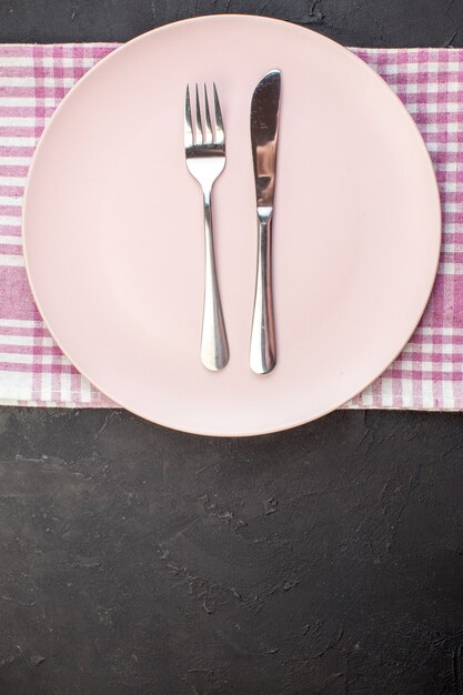 Free Photo top view pink plate with fork and knife on dark background