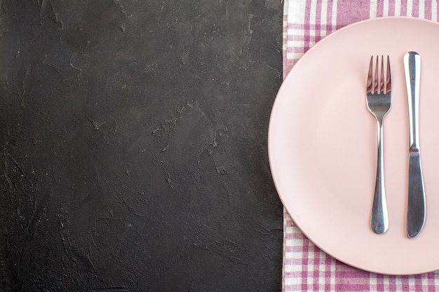 Free photo top view pink plate with fork and knife on dark surface