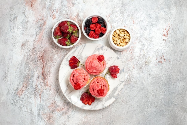 Top view of pink strawberry cakes with nuts on a white surface