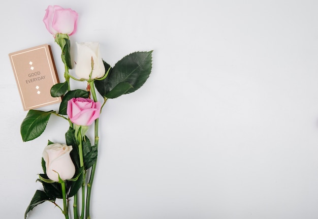 Top view of pink and white color roses with small postcard isolated on white background with copy space