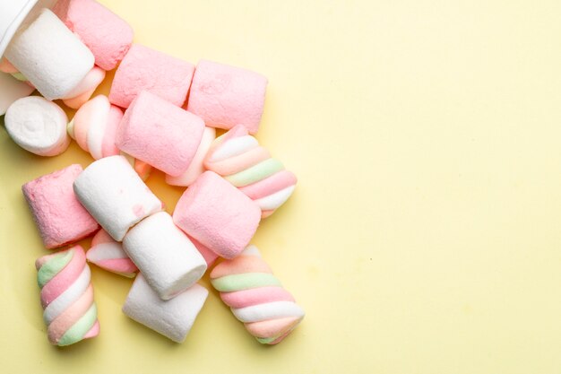 Top view of pink and white marshmallow scattered on yellow