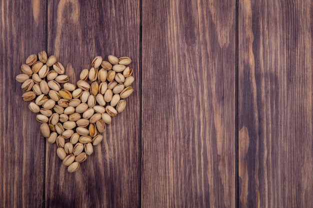 Top view of pistachios heart shaped on wooden surface