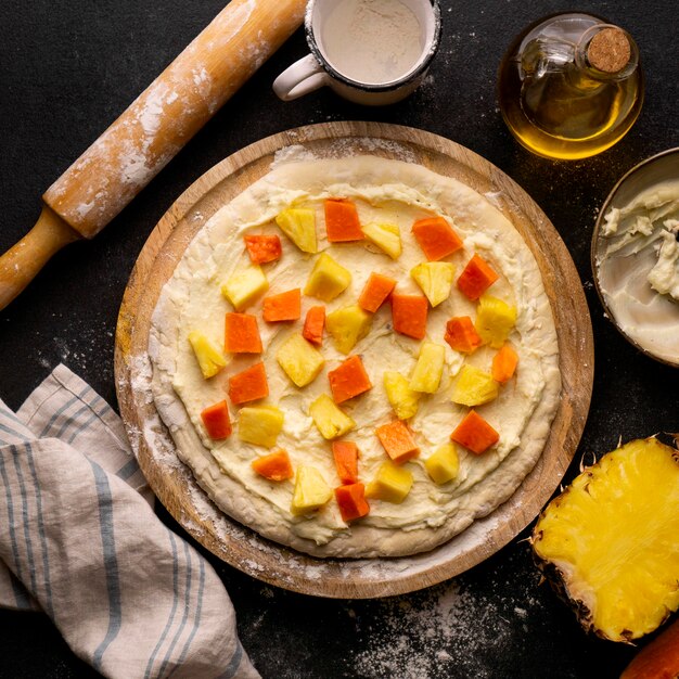 Top view of pizza dough with pineapple and papaya cubes