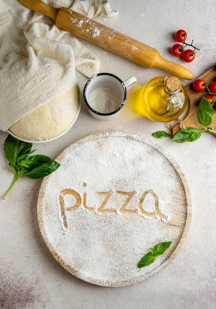 Free photo top view of pizza dough with tomatoes and word written in flour