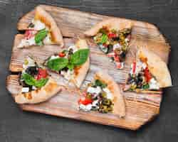 Free photo top view pizza slices on cutting board