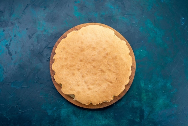 Top view plain cake dough baked round formed on dark-blue surface