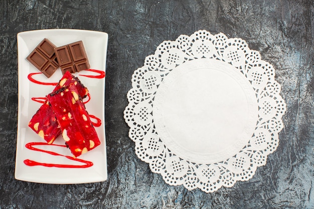 Free photo top view of a plate of chocolate bars and a piece of white lace on grey background