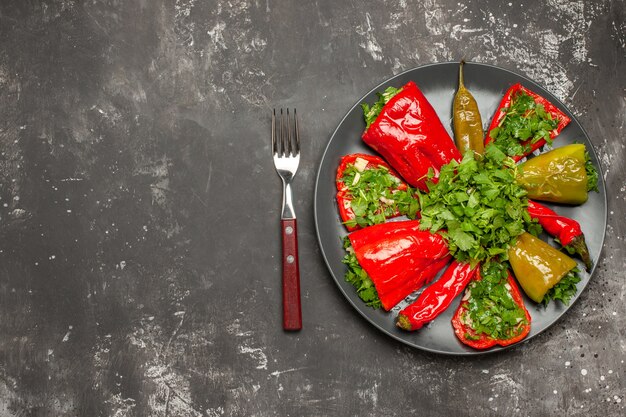 Top view of plate of peppers colorful peppers with herbs on the plate between fork and knife