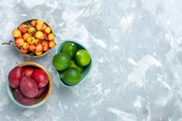 Free Photo top view of plums and lemons with sweet cherries on light white surface