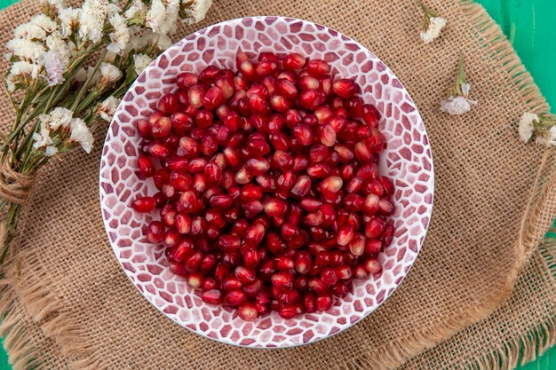 Top view of pomegranate berries with flowers on sackcloth surface