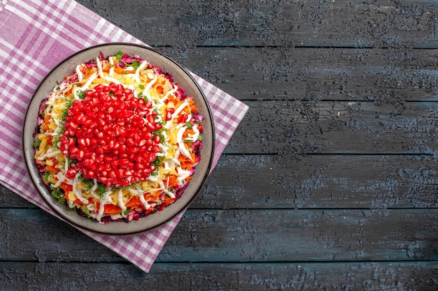 Top view pomegranate plate of appetizing dish on the pink-white checkered tablecloth on the table