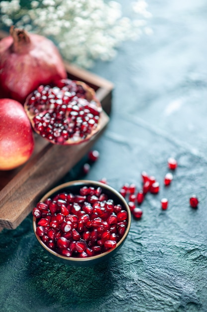 Free photo top view pomegranate seeds bowl pomegranates on wood serving board on table