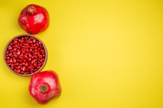 Free photo top view pomegranate two pomegranates and seeds of the appetizing pomegranate in bowl