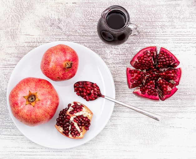 top view pomegranate on white plate and pomegranate juice on wooden table