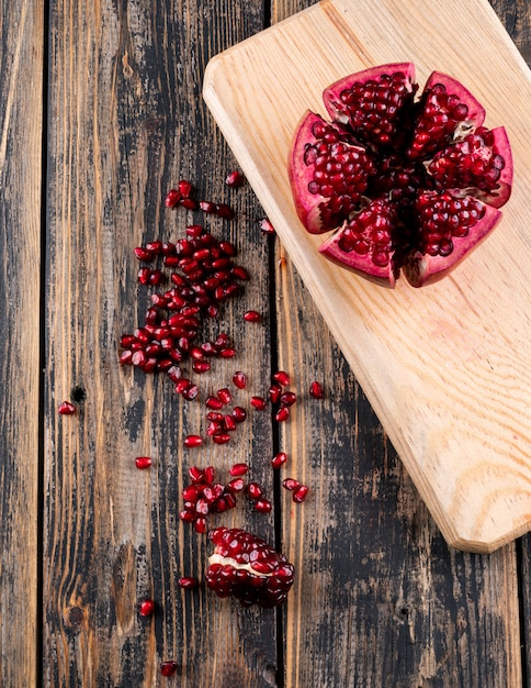 Top view pomegranate on wooden cutting board on table