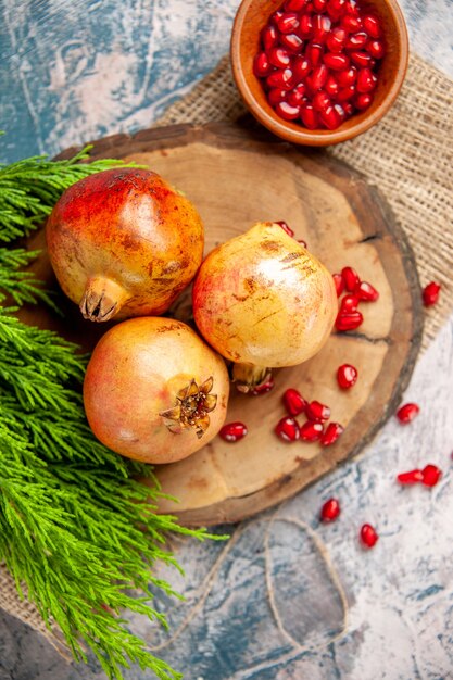 Free Photo top view pomegranates on round cutting board pomegranate seeds in bowl on blue-white surface