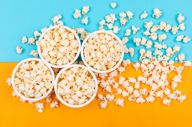 Top view of popcorn in bowls on blue and yellow  horizontal