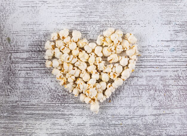 Top view of popcorn heart on white wooden  horizontal