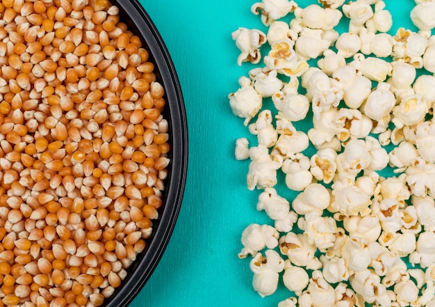 Free photo top view of popcorn seeds in black metal pan on left and prepared on right on blue surface horizontal