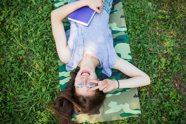 Top view portrait of a pretty young woman relaxing on a grass in park