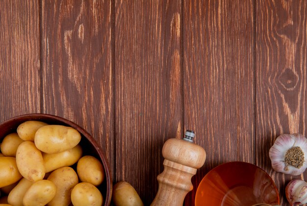 Top view of potatoes in bowl with garlic salt and butter on wooden surface with copy space