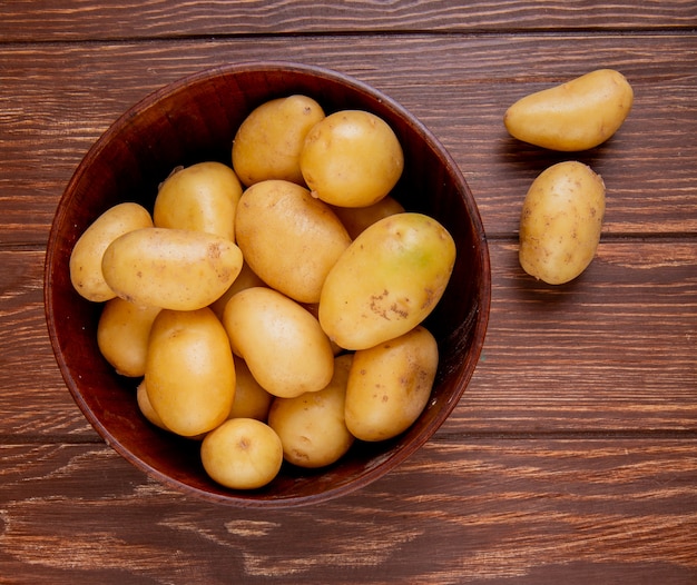 Top view of potatoes in bowl on wood