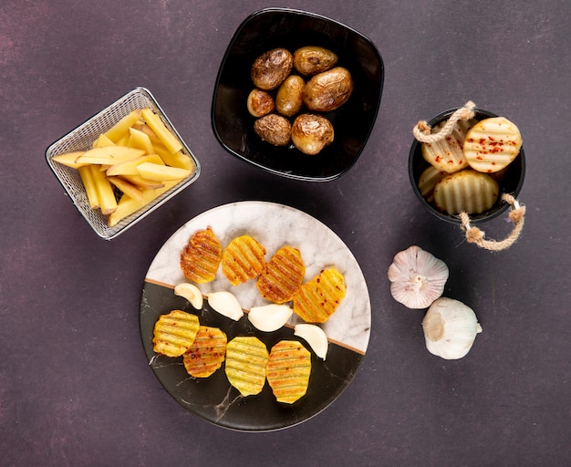 Free photo top view potatoes grilled and chopped potatoes with dried chili flakes and garlic on dark grey background