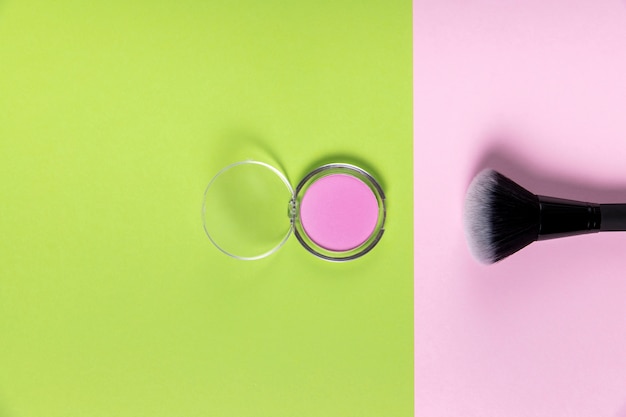 Free photo top view of powder and brush on pink and green background