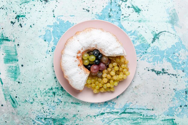 Top view  powdered cake sliced delicious with fresh grapes on light blue surface