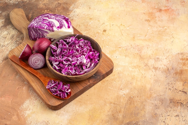 Top view preparation of fresh vegetable salad with red cabbage and onions on a cutting board on a wooden table with copy space