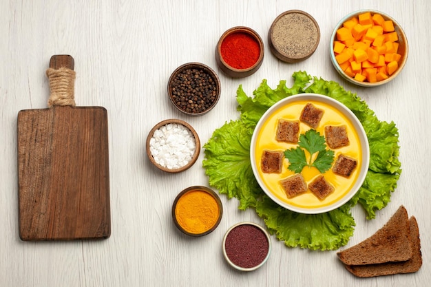 Free photo top view of pumpkin soup with little bread rusks and seasonings on white