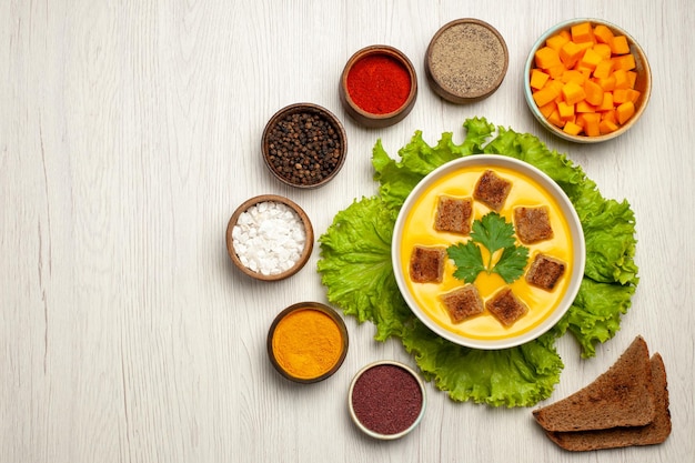 Free Photo top view of pumpkin soup with little bread rusks and seasonings on white