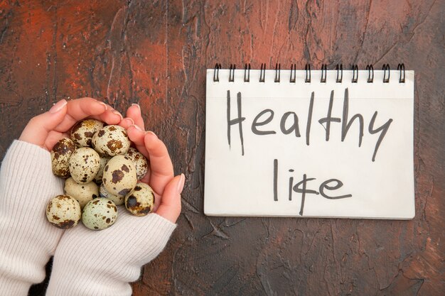 Top view quail eggs in female hands on dark table