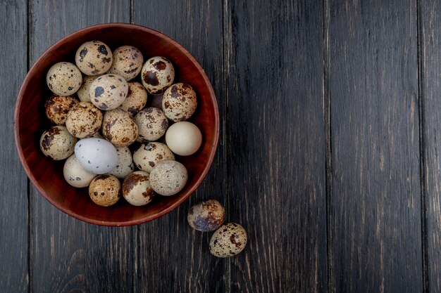 Top view of quail eggs on a wooden bowl on a wooden background with copy space