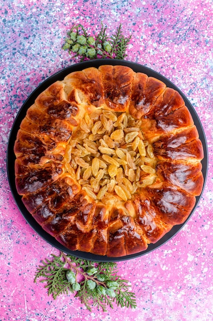 Free photo top view raisins cake baked pie cake round formed on pink desk